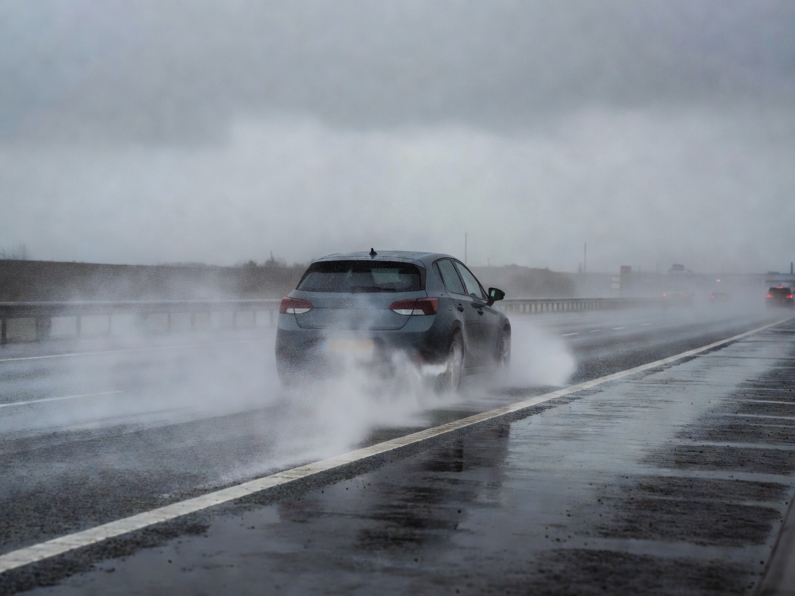 Car driving on a typical wet UK motorway with high road spray conditions in British seasonal weather